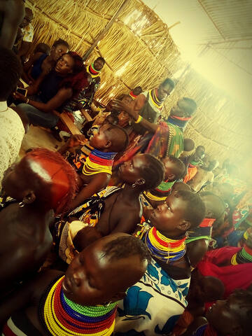 A community gathering under a thatched shelter