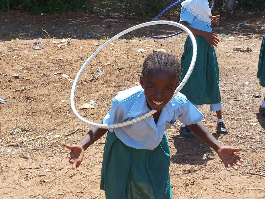 A girl mid-motion with a hula hoop, smiling